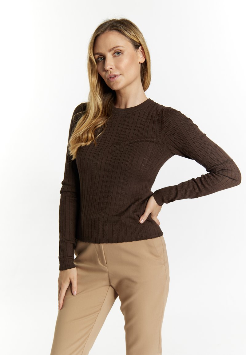 Pullover maro cu maneci lungi, cu guler rotund, purtat cu pantaloni bej. Puloverul are un model texturat și mâneci confortabil adaptate.