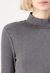Γκρι ριμπ πλεκτό μπλουζάκι με εφαρμοστή σχεδίαση, που διαθέτει ψηλό γιακά και υφή από κατακόρυφες ρίγες.