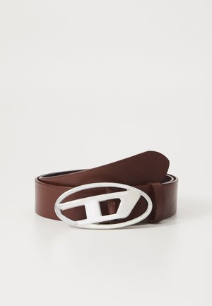 Brown leather belt with a shiny silver oval buckle featuring a cut-out design. The belt has a smooth texture and rounded ends.