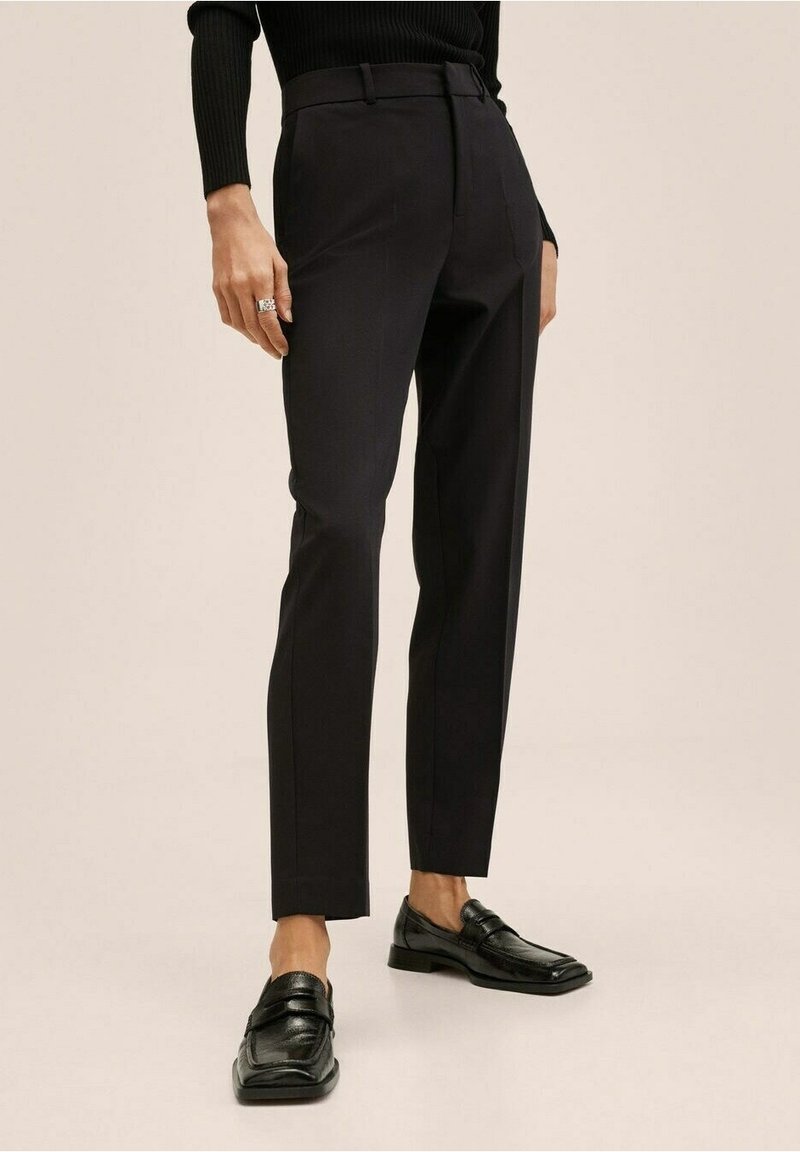 Pantalon noir sur mesure à coupe ajustée, en tissu lisse, avec un design épuré et structuré. Assorti à des mocassins en cuir noir.