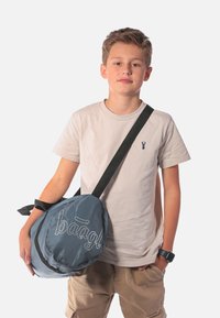 Kulatá modrá taška vyrobená z odolné tkaniny s hladkým povrchem, se bílým vyšitým logem a nastavitelným černým popruhem.