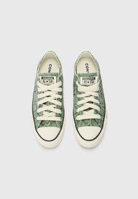 Sneakers din pânză cu model de piele de șarpe verde, cu șireturi de culoare crem, vârf din cauciuc și margine neagră pe talpă. Etichete „Converse All Star”.}}