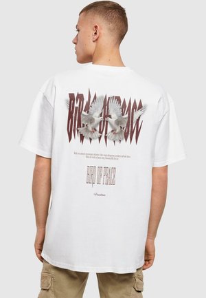 White oversized t-shirt featuring a graphic design of two doves and text on the back, with a loose fit and rolled sleeves.