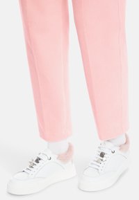 White sneakers with pink fur accents and decorative rhinestones, paired with ribbed, pastel pink tapered pants.