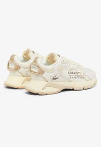 Baskets Lacoste avec des segments crème et beige, en mesh et cuir, semelle texturée, talon renforcé et accents de marque.