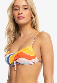 Kolorowy biustonosz bikini z marszczeniem w faliste wzory w odcieniach pomarańczowego, żółtego, niebieskiego i różowego. Cienkie regulowane ramiączka dopełniają całość.