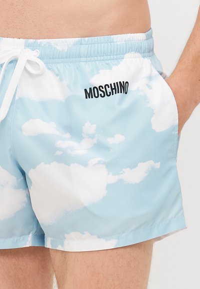 Uimashortsit vaaleansinisinä valkoisella pilvikuviolla. Varustettu joustavalla vyötärönauhalla, jossa on valkoinen nyöri ja musta "MOSCHINO" -logo.