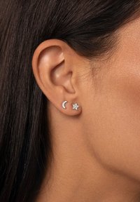 Orecchini in argento sterling con design a forma di mezzaluna e stella, ciascuno adornato con cristalli trasparenti per un ulteriore tocco di brillantezza.