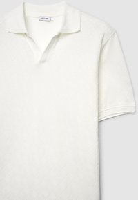 Polo blanc à manches courtes avec un motif en losanges texturé et un col classique. Dispose d'une patte de boutonnage à trois boutons et de détails côtelés.