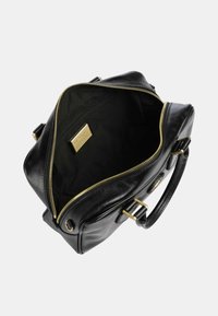 Borsa in pelle nera con zip dorata aperta, che mostra un ampio interno e un'etichetta dorata del marchio all'interno.