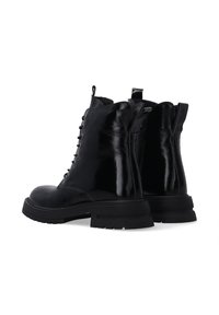 Czarne skórzane botki sięgające do kostki z błyszczącym wykończeniem, sznurowanym przodem i bocznym zamkiem błyskawicznym. Gruba gumowa podeszwa z teksturowanym gripem i tylną pętelką do zakładania.