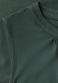 Top senza maniche verde scuro con una texture liscia. Presenta un collo tondo e pieghe sottili vicino alla cucitura della spalla. Tessuto morbido.