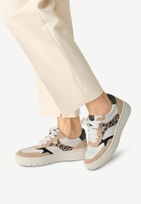 Sneakers w mieszance beżowego zamszu, czarnych skórzanych akcentów i białych paneli, z detalem w panterkę po boku i fakturowaną podeszwą.