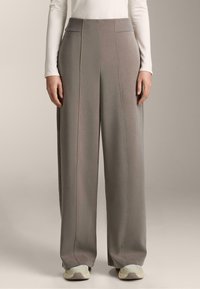 Svetlošedé široké nohavice vyrobené z mäkkej tkaniny, s vysokým rebrovaným pásom, viditeľnými švovými detailmi a uvoľneným strihom.