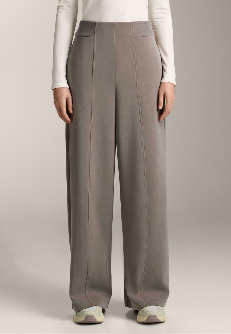 Svetlošedé široké nohavice vyrobené z mäkkej tkaniny, s vysokým rebrovaným pásom, viditeľnými švovými detailmi a uvoľneným strihom.