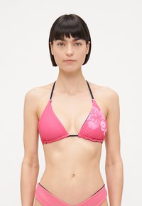 Ružičasti bikini top s trokutastim čašama, crnim trakama i cvjetnim uzorkom s jedne strane. Izrađen od glatkog, rastezljivog materijala.