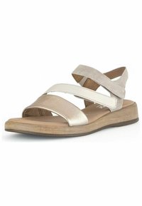 Sandali piatti con cinturini in pelle e suede beige, caratterizzati da un design incrociato e un plantare imbottito su una suola con texture legno chiaro.