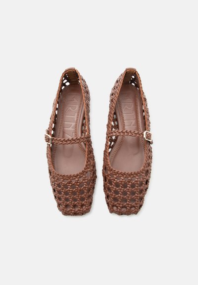 Pruunist kootud nahast Mary Jane stiilis madalad kingad nelinurksete varvaste ja väikeste kuldselt tooni pandlatega rihmadega, nähtud ülalt valgel taustal.