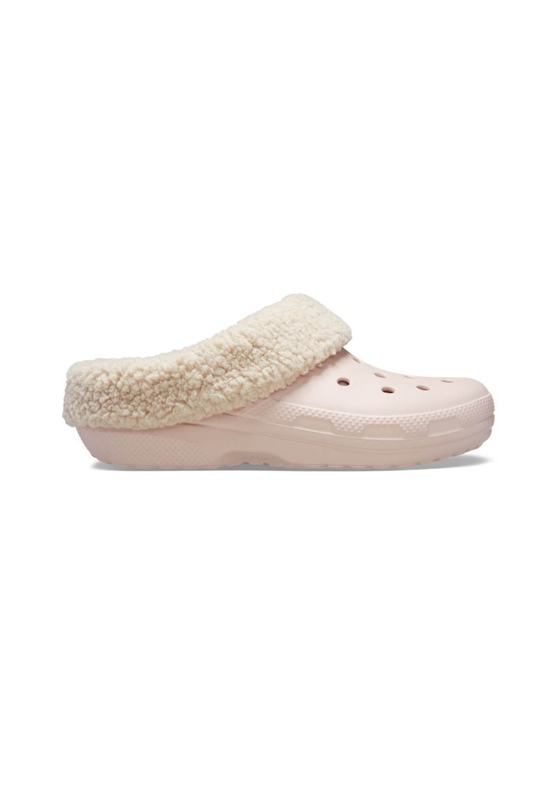 Zuecos de color rosa claro con forro de felpa beige y agujeros de ventilación, diseñados para un uso casual en interiores o exteriores.
