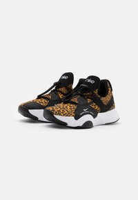 Zapatillas deportivas de estampado de leopardo negro y naranja con suela blanca redondeada y acentos negros, que cuentan con cierre con cordones y logo en la lengüeta.
