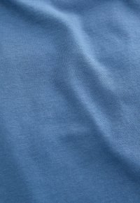 Modrá bavlnená látka s hladkým povrchom, ktorý má jemne rebrovaný vzor a subtilné svetlé odtiene v rôznych oblastiach.
