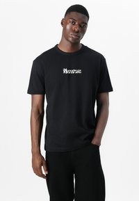 Black cotton t-shirt featuring a white graphic logo on the chest. Short sleeves and a round neckline, designed for a relaxed fit.