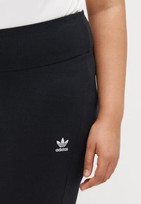 Fekete bordázott leggings, magas derékkal, bal oldalon a csípő közelében egy kis fehér Adidas logóval. Puha, rugalmas anyag.