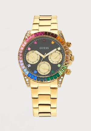 Montre-bracelet en métal doré avec cadran noir, trois sous-cadrans et pierres précieuses aux couleurs de l’arc-en-ciel entourant la lunette, étiquetée GUESS.