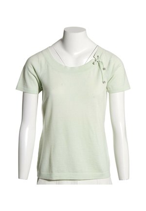 Chemise vert clair à manches courtes avec un col rond et un détail noué décoratif sur l'épaule gauche sur un mannequin blanc.