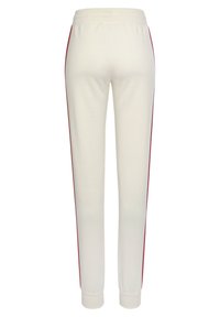 Weiße Jogginghosen mit roten Seitenstreifen, elastischem Bündchen und engen Bündchen. Hergestellt aus weichem, glattem Stoff.