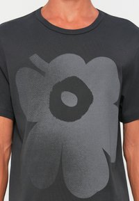 T-shirt nera in cotone con un grande motivo floreale grigio al centro, girocollo solido e maniche corte.