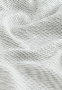 Tessuto testurizzato in grigio chiaro e bianco, con un motivo a griglia sottile. Morbido e leggero con una finitura liscia.