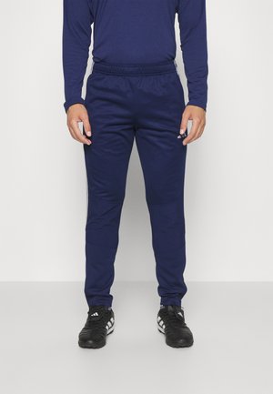 Pantalones deportivos de color navy con cintura elástica, bolsillos laterales y corte ajustado. Hechos de una tela ligera y suave, combinados con zapatillas deportivas negras.