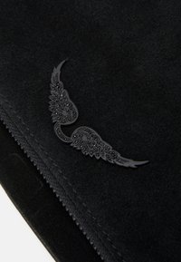 Sort ruskindspose med et forhøjet, dekorativt sort vingsdesign med indviklede detaljer. Lynlåslukning langs en kant.