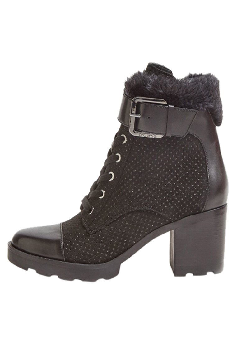 Bottine noire avec tissu texturé et accents en cuir lisse, dotée d'un col en fourrure, d'une sangle à la cheville avec boucle en métal et d'un talon épais.