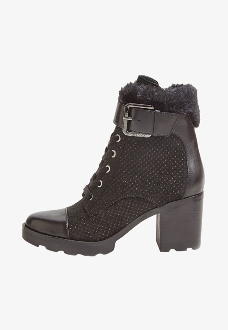Bottine noire avec tissu texturé et accents en cuir lisse, dotée d'un col en fourrure, d'une sangle à la cheville avec boucle en métal et d'un talon épais.