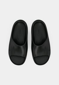 Μαύρες ελαστικές σαγιονάρες με φαρδύ λουρί, λεία επιφάνεια και ανατομική σόλα, σχεδιασμένες για άνεση και εύκολη χρήση.