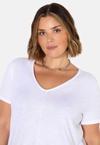 V-kauluksellinen valkoinen lyhythihainen t-paita, joka on valmistettu kevyestä kankaasta. Tässä paidassa on hieman teksturoitu pinta ja rento malli.