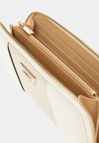 Portefeuille crème en matériau texturé, avec une fermeture éclair dorée et des fentes pour cartes à l'intérieur, ainsi qu'un compartiment zippé.