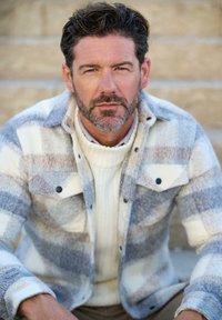 Grau-weißer karierter Flanellhemd mit kontrastierenden Streifen, ausgestattet mit schwarzen Knöpfen und zwei Brusttaschen, über einem weißen Rollkragenpullover getragen.