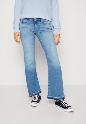 Světle modré rozšířené džíny z denimu, s vybledlým ombré vzhledem, surovým lemem a v kombinaci s černými teniskami. Měkká textura, volný střih.