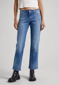 Ljusblå denimjeans med hög midja, trasig nederkant, två framfickor och en avslappnad passform. Kombinerat med svarta klumpiga klackboots.