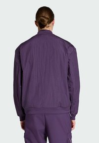 Purple bomber jacket made of crumpled fabric, featuring a ribbed collar and cuffs, with a relaxed fit and back seam detailing.