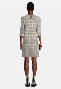 Rutigt klänning med trekvartsärmar, nyckelhålsrygg och skräddarsydd passform i beige, svart och gula nyanser; bärs med ankelstövlar.