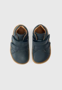 Pantofi pentru bebeluși din piele albastru închis, cu finisaj texturat, prevăzuți cu două curele cu velcro și talpă din cauciuc maro deschis, design cu vârf rotund.