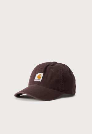 Тъмнокафява бейзболна шапка Carhartt с извита козирка и бяло лого отпред на светъл едноцветен фон.