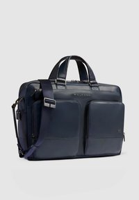 Cartella in pelle blu navy con due tasche frontali, doppie maniglie superiori e tracolla removibile. Presenta una texture liscia e accessori robusti.