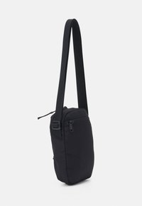 Borsa a tracolla nera con forma rettangolare, realizzata in tessuto resistente, dotata di chiusura con zip e tracolla regolabile. Inclusa tasca laterale.