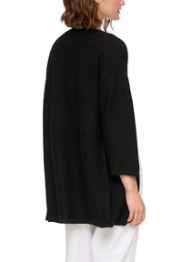 Schwarzer übergroßer Pullover mit lockerer Passform, abgesenkten Schultern und ärmellangen, mittellangen Ärmeln aus strukturiertem Strickstoff.