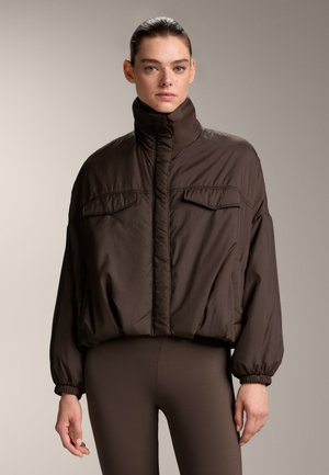 Giacca marrone imbottita con colletto alto, due tasche frontali e polsini elasticizzati. Realizzata in materiale leggero e liscio.